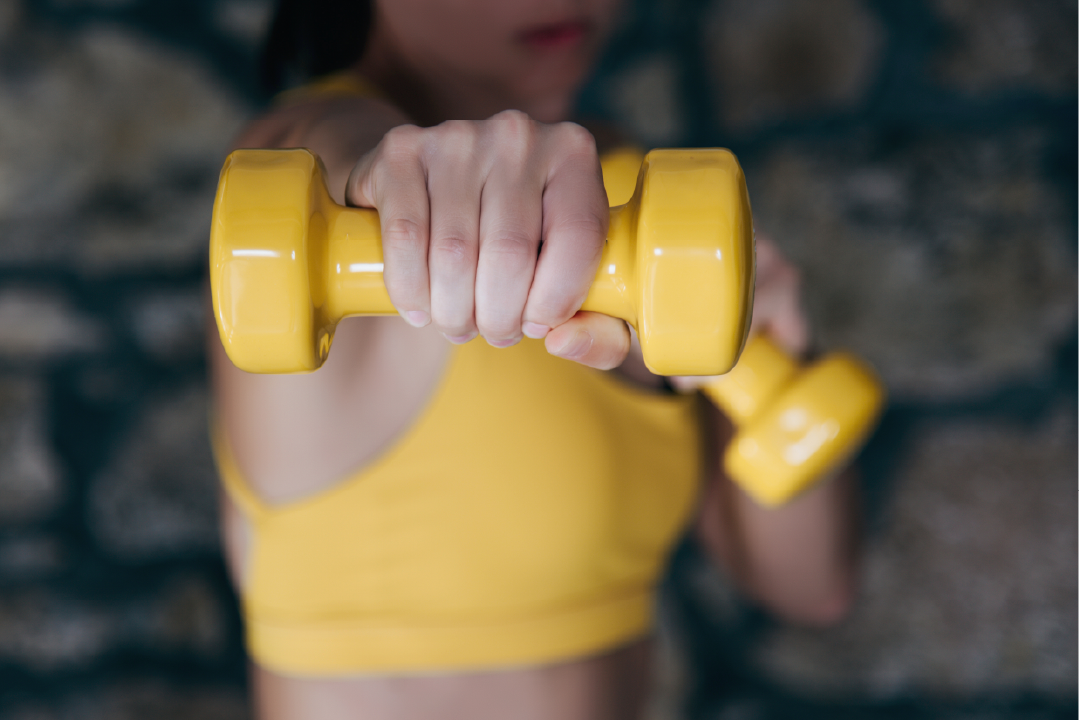 Woman punching forward with a yellow weight in hand; personal training interviews