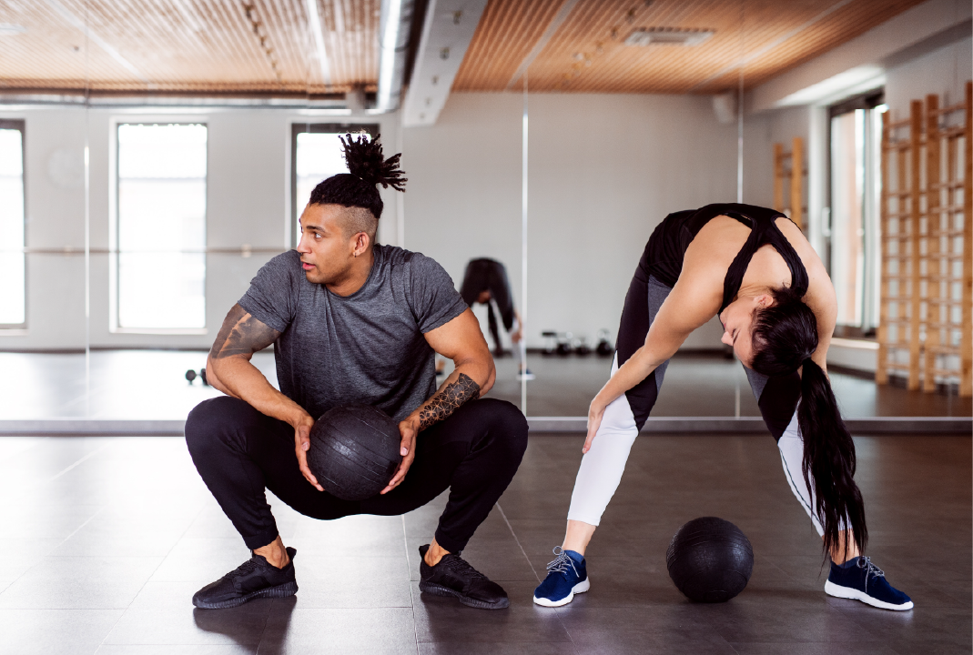 Two people stretching with a weight ball; make more money personal training