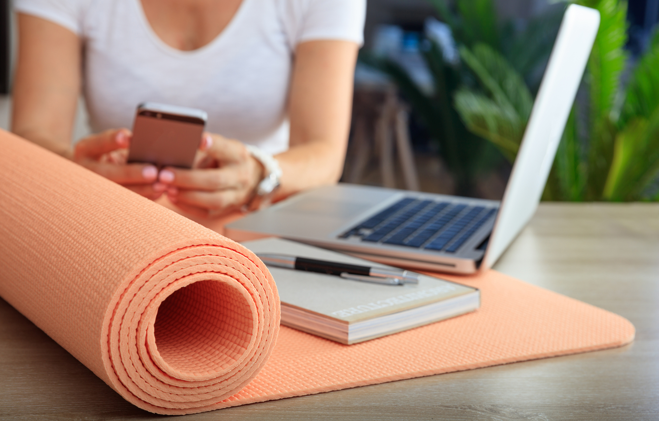 Yoga mat, notebook, and electronics on a table; best personal training software